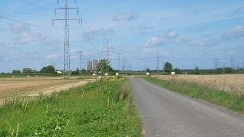 Weg zwischen Feldern mit Strommasten