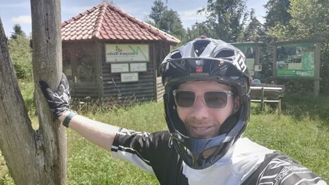 Herr Patrick Reitz mit Helm und Sonnenbrille sich an einem Baum abstützend