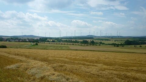 Wolfhagen-Istha Felder mit Büschen dazwischen, im Hintergrund Windräder