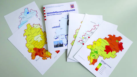Immobilienmarktbericht Mehrere Seiten des Immobilienmarktberichtes liegen überlappend auf einem Schreibtisch