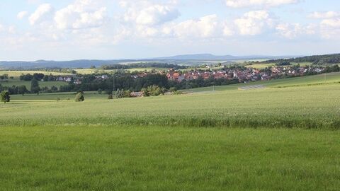 Blick über Wiese zu einem Dorf