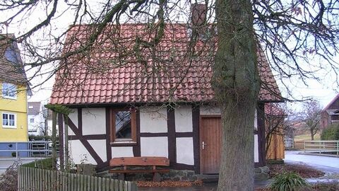 Holzbank und Baum vor einem Fachwerkhaus
