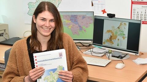 Auszubildende am Schreibtisch mit einem Heft in den Händen