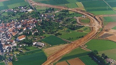 Luftbild einer Baustelle, Ortsumgehungsstraße in einem Linksbogen, linke Bildseite: Häuser