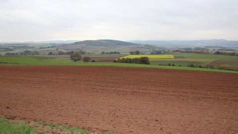 Ackerfläche vor hügeliger Landschaft