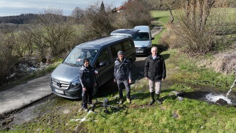 3 Menschen mit Drohne vor 2 PKW