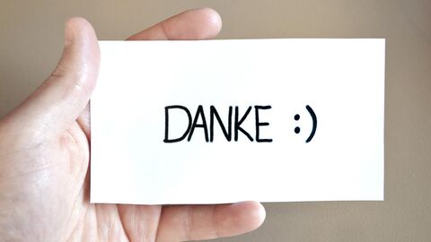 Hand mit Zettel auf dem Danke steht