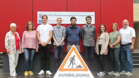 Ausbildungsstart 2023, Amt für Bodenmanagement Heppeneim 9 Menschen nebeneinander, im Vordergrund ein Baustellenschild mit dem Text Ausbildung