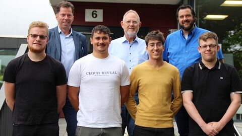 7 Menschen auf einer Treppe in zwei Reihen, vorne 4, dahinter 3