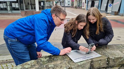 2 Mädchen mit einem Betreuer an einem geodätischen Referenzpunkt