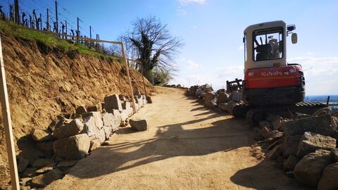 Feldweg am Hang, auf der rechten Seite ein kleiner Bagger