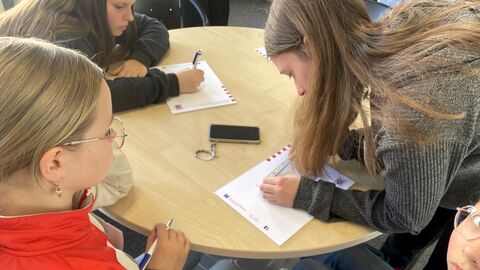 Drei Personen beugen sich über einen runden Tisch