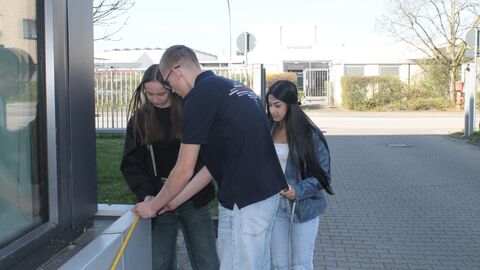 Mehrere Personen beim messen mit einem Maßband