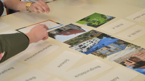 Zwei Hände an einem Tisch auf dem Bilder liegen