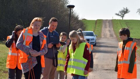 Mehrere Personen auf einem Feldweg mit Instrumenten zur Satellitenvermessung