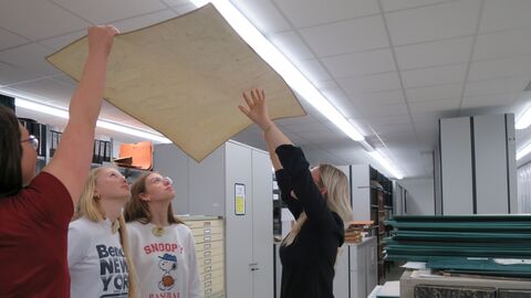 Vier Personen schauen von unten auf eine alte Karte