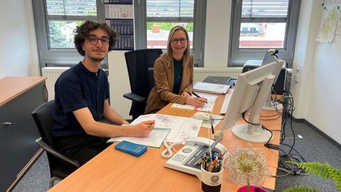 Efe Berk und Svetlana Könitzer an einem Schreibtisch