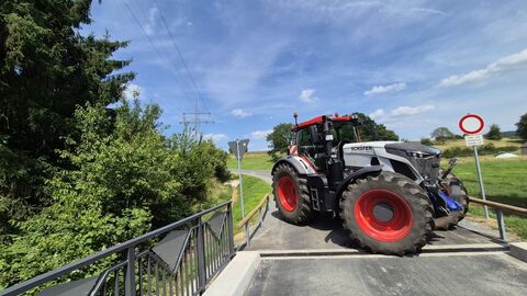 Traktor quer vor einer Brücke