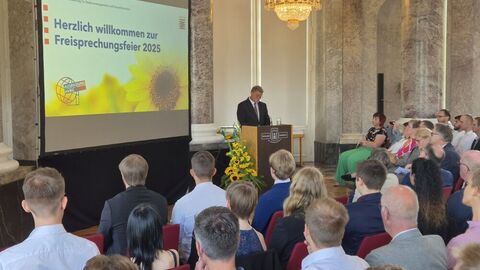 Redner am Pult vor Publikum