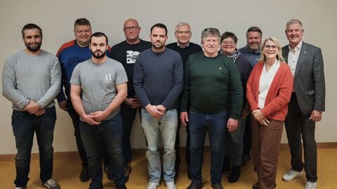 11 Personen nebeneinander vor einer Wand