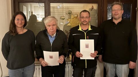 4 Personen in einem Innenraum, 2 mit einer Urkunde in den Händen