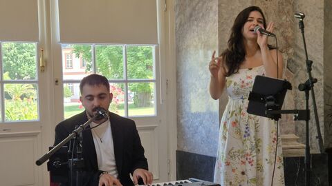 Musiker sitzt am Keyboard, Sängerin steht am Mikrofon